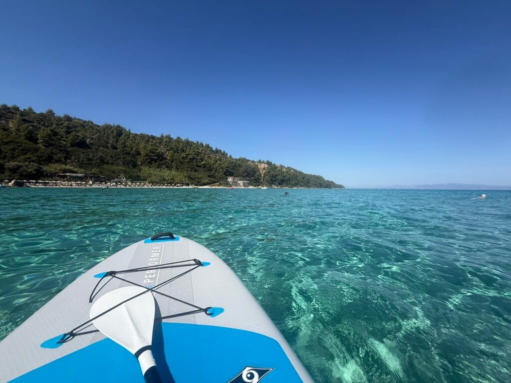 Paddleboarding in the turquoise water below Ta Glarakia taverna in Afytos, Halkidiki